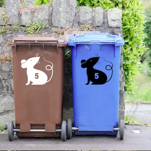 May include: Two recycling bins with mouse stickers. The bin on the left is brown and the bin on the right is blue. Both bins have a mouse sticker with the number 5 on it. The mouse on the left bin is white and the mouse on the right bin is black.