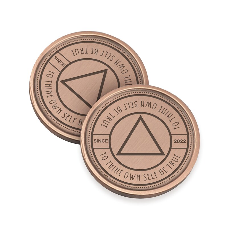 May include: Two copper-colored coins with the inscription "To thine own self be true" and a triangle design. The inscription "Since 2022" appears on one of the coins.