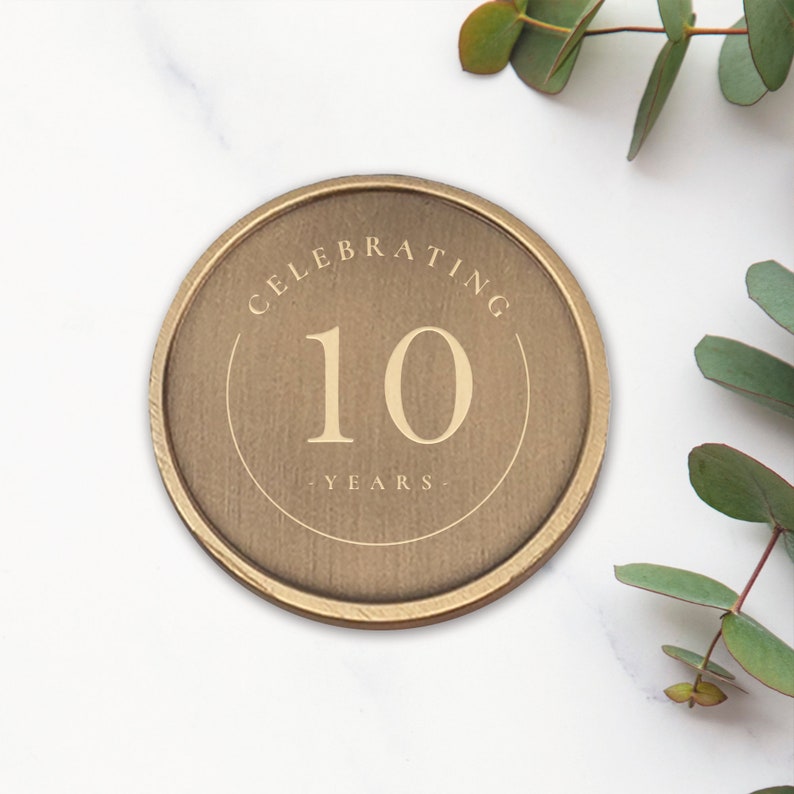 May include: A gold-colored round metal token with the text "Celebrating 10 Years" engraved on it.