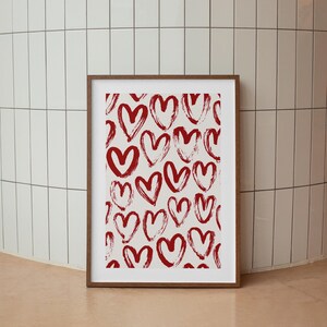 May include: A framed print with a white background and a pattern of red hand-drawn hearts.