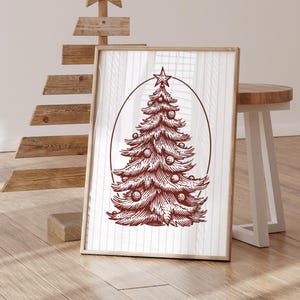 May include: A framed Christmas tree art print. The illustration features a detailed, reddish-brown Christmas tree with ornaments and a star on top, set within an oval frame. The artwork is displayed on a white background with vertical lines.