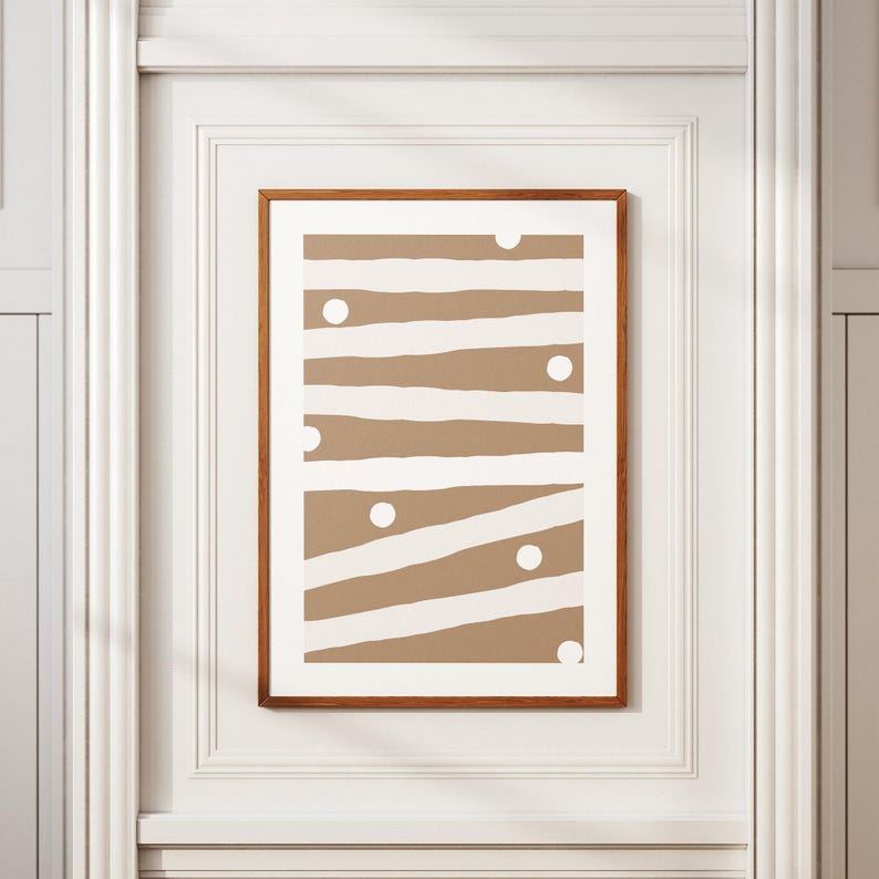 Op de afbeelding: Een ingelijst print met een bruin en wit abstract ontwerp. Het ontwerp heeft witte strepen en cirkels op een bruine achtergrond.