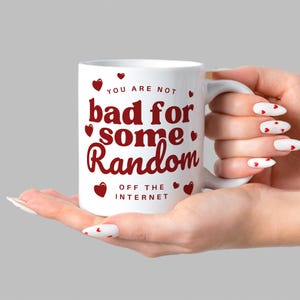 Puede incluir: Taza de cer&aacute;mica blanca con un gr&aacute;fico rojo que dice "You are not bad for some random off the internet" con corazones rojos alrededor del texto.
