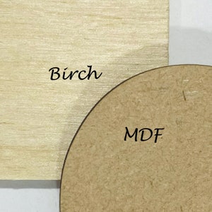 May include: Close-up of two wood samples. One is a light-colored rectangular piece of birch wood. The other is a rounded, brown MDF (medium-density fiberboard) piece. The word "Birch" is written on the birch wood, and the letters "MDF" are written on the MDF piece.