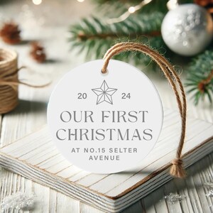 May include: White round Christmas ornament with the text "Our First Christmas at No. 15 Selter Avenue" and a star design with the numbers 20 and 24.