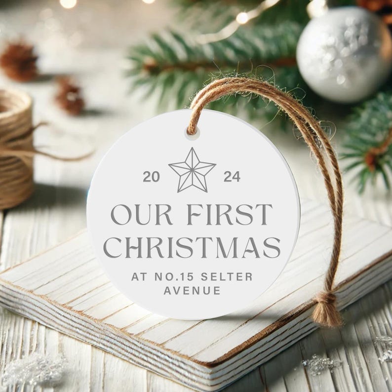 May include: White round Christmas ornament with the text "Our First Christmas at No. 15 Selter Avenue" and a star design with the numbers 20 and 24.