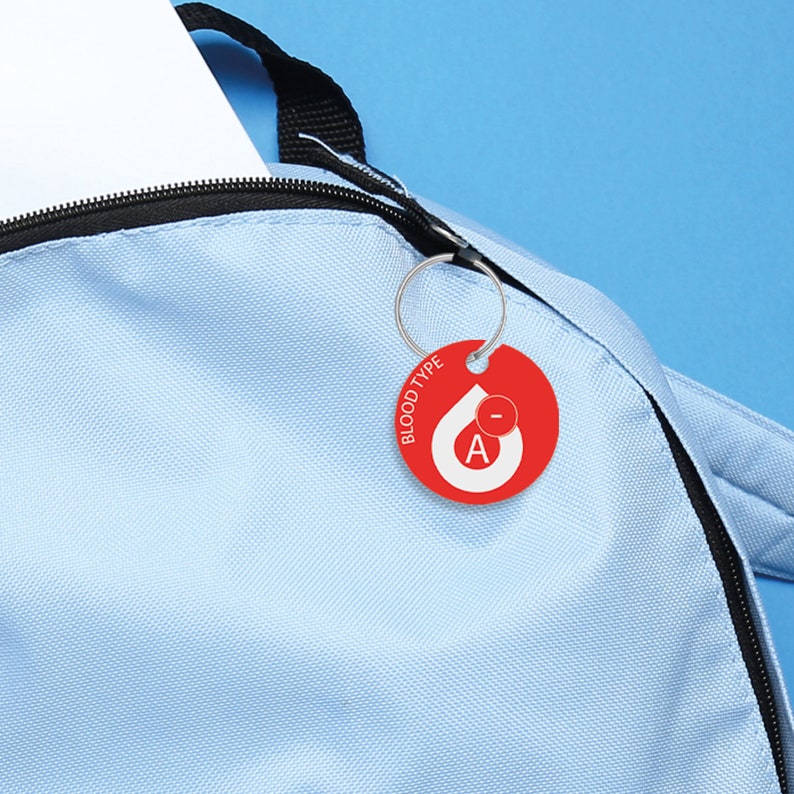 May include: A light blue backpack with a red blood type tag attached to the zipper. The tag says "Blood Type" and has a red drop with a white "A-" inside.