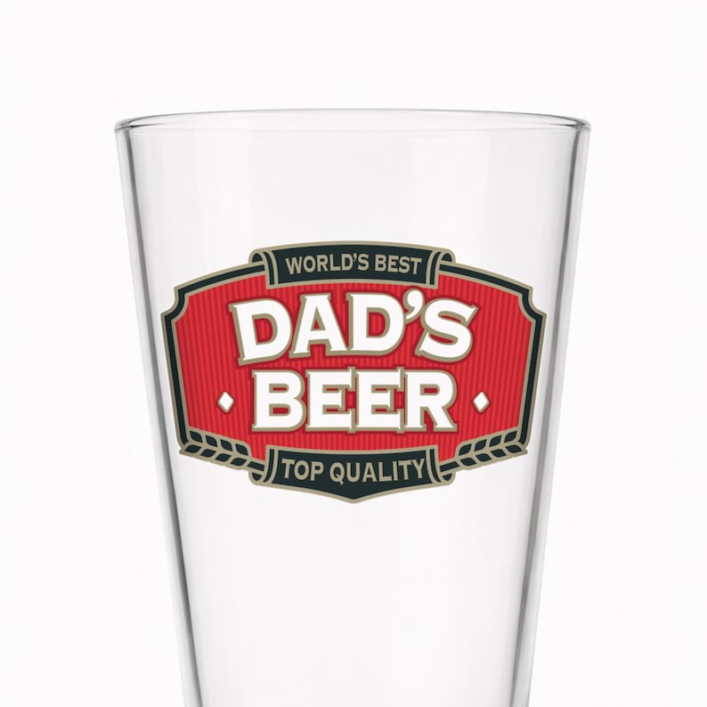 May include: A clear beer glass with the words "WORLD'S BEST DAD'S BEER TOP QUALITY" in a red and black design. The glass is empty and has a classic pint shape, perfect for enjoying a cold beer.