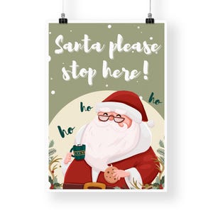 May include: A green and white Christmas sign with Santa Claus holding a cup of hot chocolate and a cookie. The sign says "Santa please stop here!" with "ho ho ho" written around Santa.