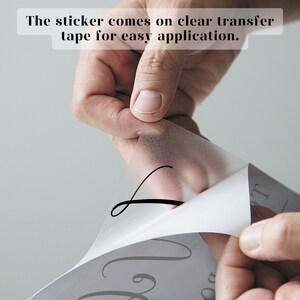May include: A clear transfer tape is being peeled off a white sticker with black lettering that reads "Love You To The Moon And Back".