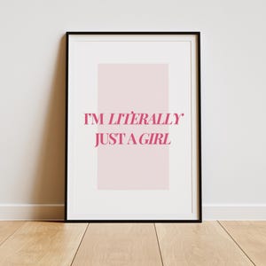 May include: A black framed print with a pink background and the text "I'M LITERALLY JUST A GIRL" in pink.