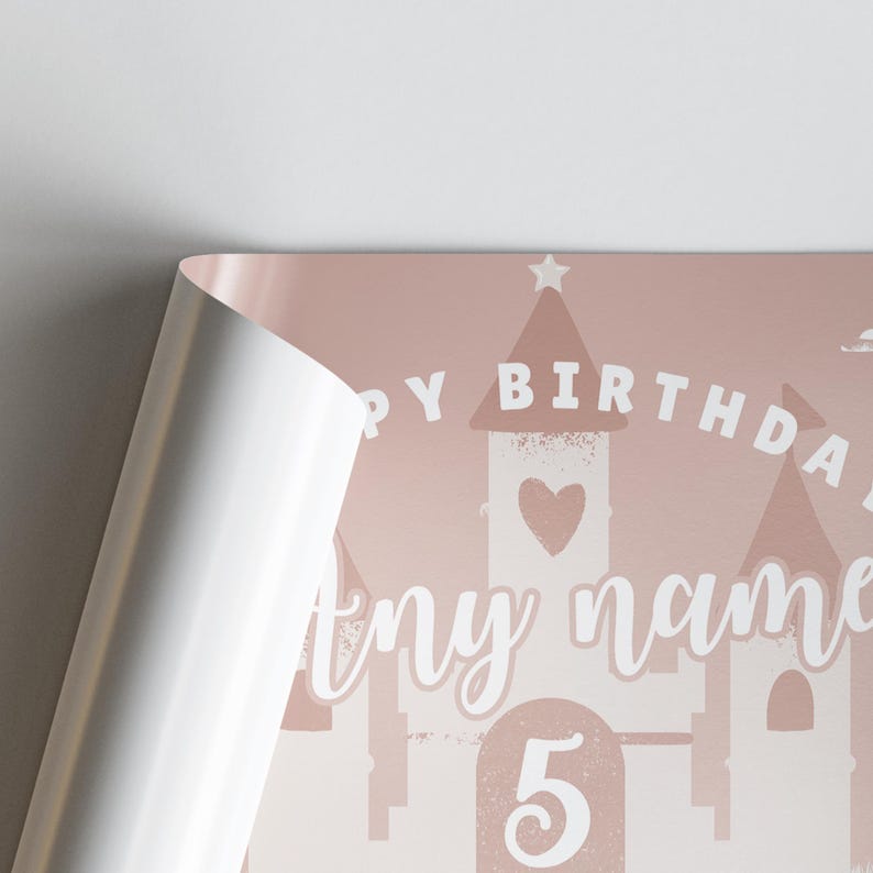May include: A pink birthday poster with a castle design. The words "Happy Birthday" are arched above the castle, with space for a name and the number "5" below. The poster is partially rolled.