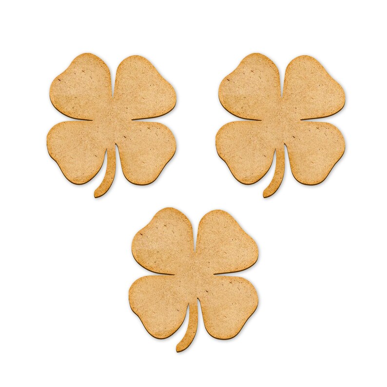 May include: Three wooden four-leaf clovers arranged on a white background. Each clover has four rounded leaves and a stem. The clovers are a light brown color and appear to be cut from wood.