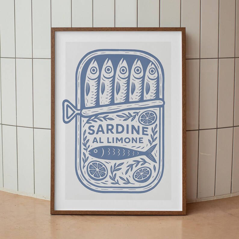 May include: A framed art print featuring a blue illustration of a sardine can. The can is labeled "SARDINE AL LIMONE" and contains sardines, lemon slices, and decorative elements. The print is in a brown frame.