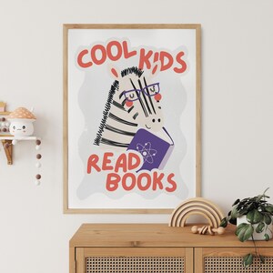 May include: A framed print with a white background and a zebra wearing glasses and reading a book. The text on the print reads "Cool Kids Read Books".