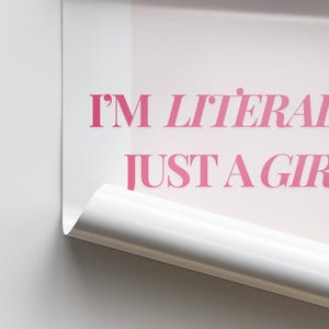 May include: A white poster with pink text that reads "I'm literally just a girl". The poster is partially rolled up at the bottom.