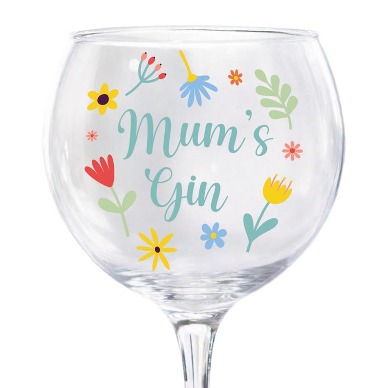 Może przedstawiać: Przezroczysty kieliszek do ginu z napisem "Mum's Gin" w kolorze turkusowym, otoczony kolorowymi kwiatowymi wzorami. Kwiaty są ż&oacute;łte, czerwone i niebieskie, z zielonymi liśćmi. Kieliszek przeznaczony jest do koktajli ginowych.