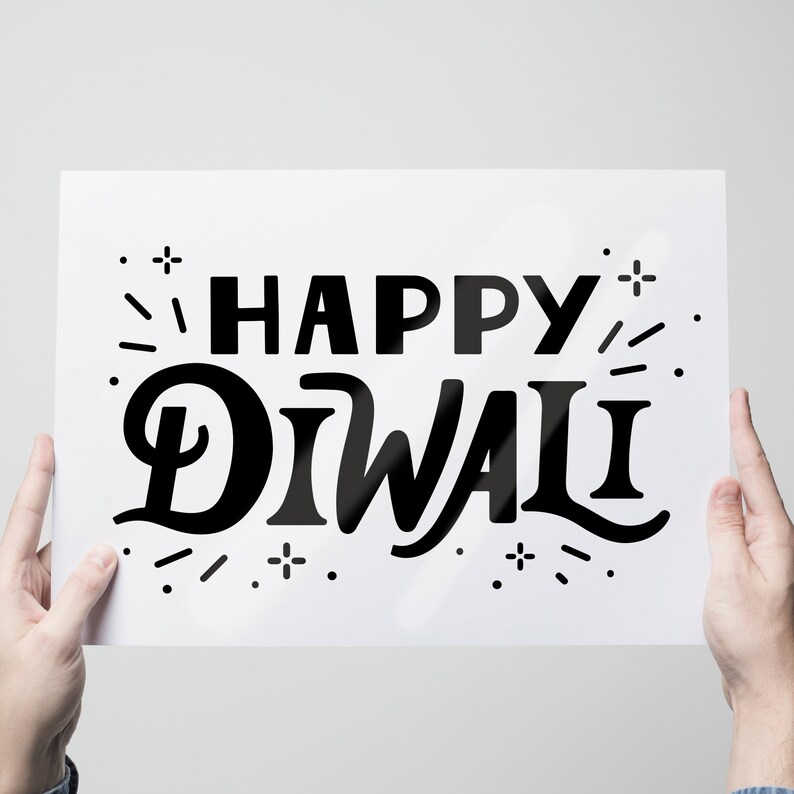 May include: A white sign with black text that reads "Happy Diwali" with a stylised design of fireworks around the text.