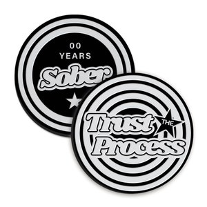 May include: Two black and white circular coins with a white star and text. The first coin says "00 YEARS SOBER" and the second coin says "TRUST THE PROCESS".
