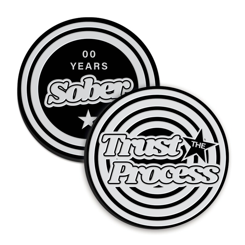 May include: Two black and white circular coins with a white star and text. The first coin says "00 YEARS SOBER" and the second coin says "TRUST THE PROCESS".