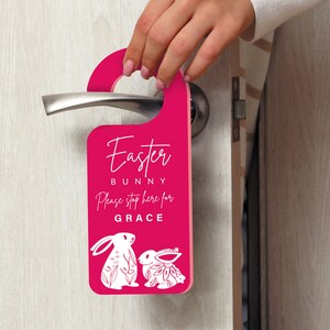 May include: Pink door hanger with the text "Easter Bunny" and "Please stop here for GRACE". Two white bunny illustrations are at the bottom of the hanger.