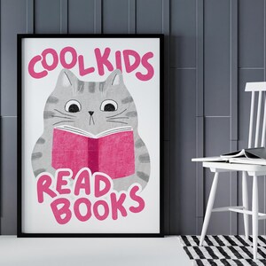 May include: A white poster with a gray cat reading a pink book. The text on the poster says "Cool Kids Read Books".