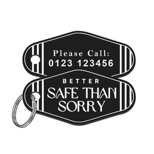 Może przedstawiać: Czarno-biała breloczek do kluczy z napisem "Please Call: 0123 123456" i "Better Safe Than Sorry". Brelok ma dołączony srebrny brelok. Projekt jest w stylu retro.
