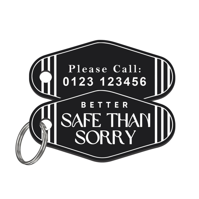 Może przedstawiać: Czarno-biała breloczek do kluczy z napisem "Please Call: 0123 123456" i "Better Safe Than Sorry". Brelok ma dołączony srebrny brelok. Projekt jest w stylu retro.