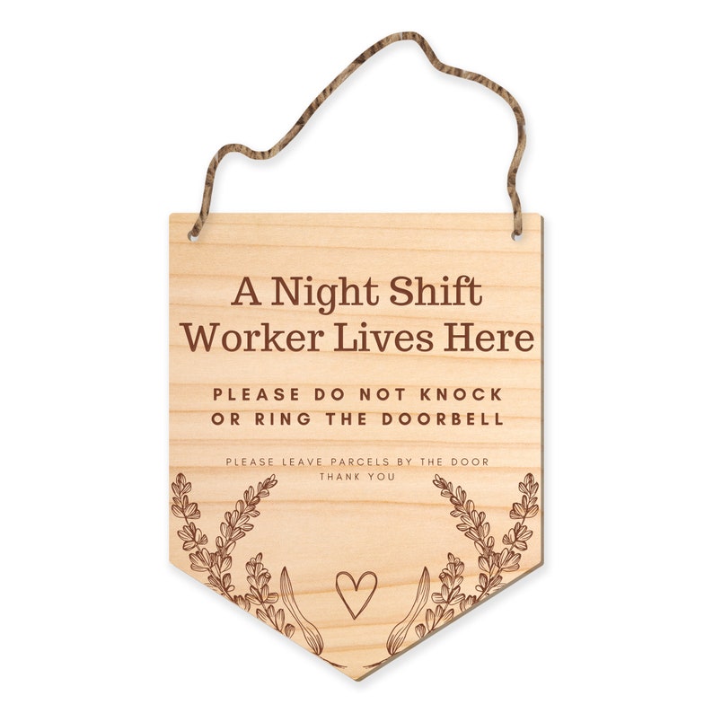May include: Wooden sign with the text "A Night Shift Worker Lives Here." It also says "PLEASE DO NOT KNOCK OR RING THE DOORBELL" and "PLEASE LEAVE PARCELS BY THE DOOR THANK YOU." The sign has a heart and floral design.