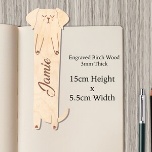 May include: A wooden bookmark shaped like a dog with the name "Jamie" engraved on it. The bookmark is 15 inches tall and 5.5 inches wide. It is made of birch wood and is 3 mm thick.