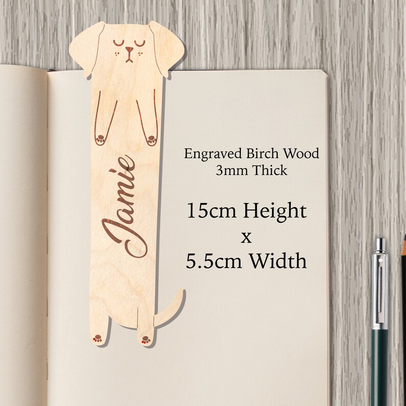 May include: A wooden bookmark shaped like a dog with the name "Jamie" engraved on it. The bookmark is 15 inches tall and 5.5 inches wide. It is made of birch wood and is 3 mm thick.