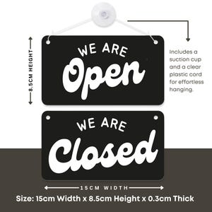 May include: A black and white reversible sign with the words "WE ARE Open" and "WE ARE Closed". The sign is 15cm wide and 8.5cm high, and includes a suction cup and clear plastic cord for hanging.