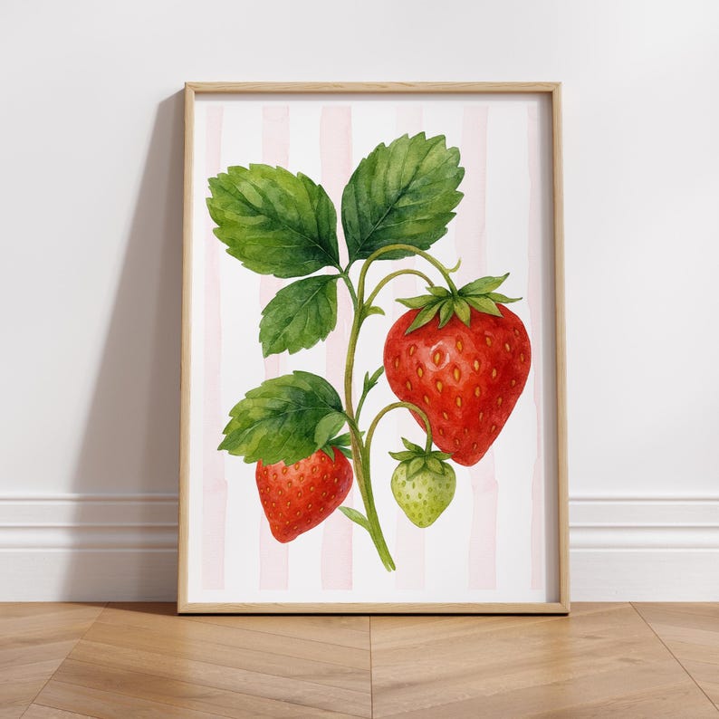 May include: A framed watercolor print of a strawberry plant. The image features three ripe red strawberries and one unripe green strawberry, with green leaves and stems. The background has pink and white vertical stripes.