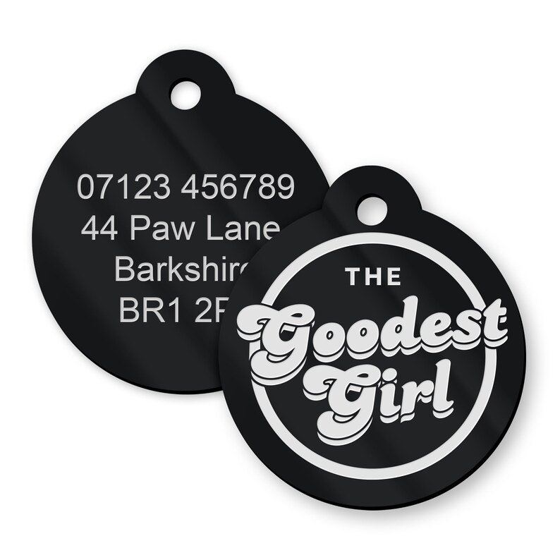 May include: Two black round pet ID tags. One tag has a phone number, address, and postcode. The other tag has white text that reads "THE GOODEST GIRL" in a retro font.