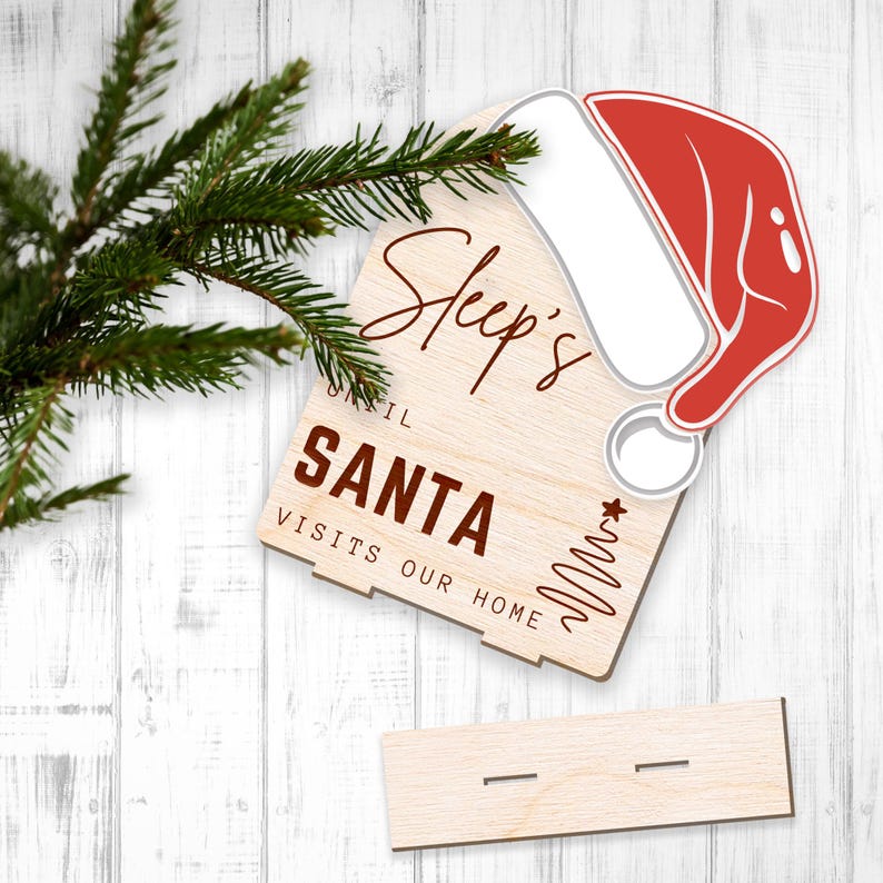 May include: Wooden sign with the text "Sleep's until Santa visits our home" and a red and white Santa hat.