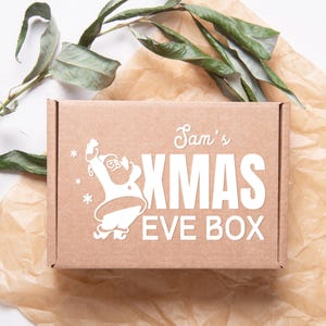 May include: A brown cardboard box with a white design featuring a cartoon Santa Claus, the text "Sam's Xmas Eve Box", and snowflakes.