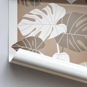 May include: A close-up of a brown and white patterned wallpaper with a tropical leaf design. The wallpaper is rolled up and the edge is visible.