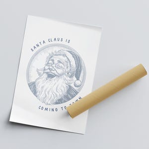 May include: A white poster with a blue illustration of Santa Claus laughing. The text "SANTA CLAUS IS COMING TO TOWN" is written in blue below the illustration.