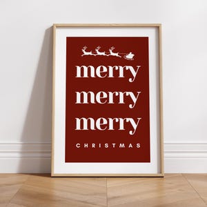 May include: A framed Christmas print with a red background and white text. The words "merry merry merry" are stacked vertically, with "CHRISTMAS" at the bottom. A white illustration of Santa's sleigh and reindeer is at the top.