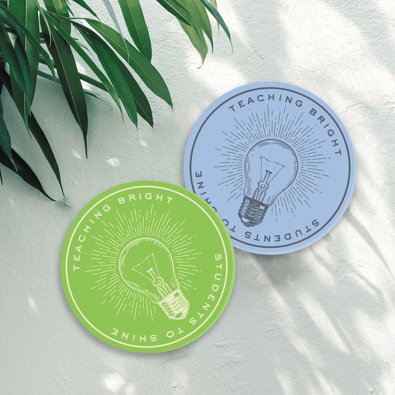 May include: Two round stickers with a lightbulb graphic and the text "Teaching Bright Students to Shine" in a circle around the lightbulb. The sticker on the left is green and the sticker on the right is blue.