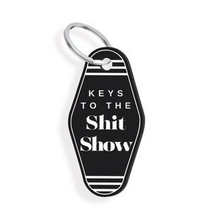 May include: Black motel key chain with white text that reads "Keys to the Shit Show".