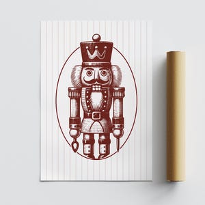May include: A print of a nutcracker soldier in a maroon color, with a crown and mustache, inside an oval frame. The background is white with vertical stripes. A rolled-up poster is on the right.
