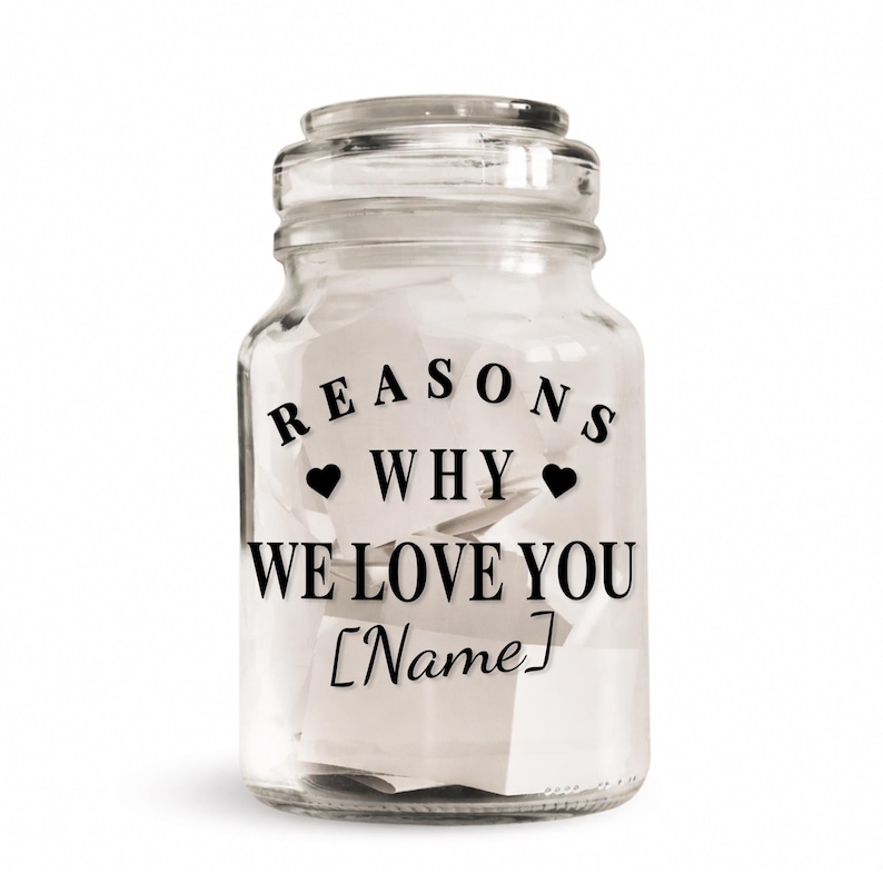 May include: A clear glass jar with a lid, filled with white paper notes. The jar has black text that reads "REASONS WHY WE LOVE YOU [Name]" with heart symbols. The jar is on a white background.