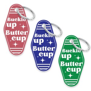 May include: Three keychains shaped like motel room keys with the text "Buckle up Buttercup" in white on a red, blue, and green background.