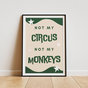 May include: A green and white print with the text "Not my circus, not my monkeys" on a beige background. The print is framed in a black frame.