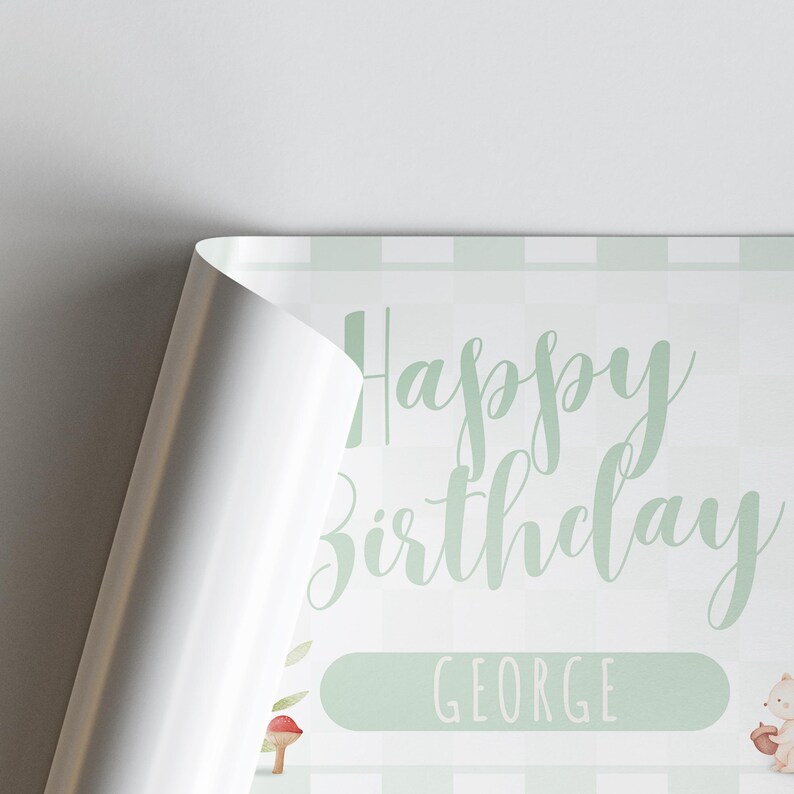 May include: A birthday-themed print with the words "Happy Birthday George" in a soft green script. The background has a subtle checkered pattern in light green. A corner of the print is folded over, revealing a white edge.