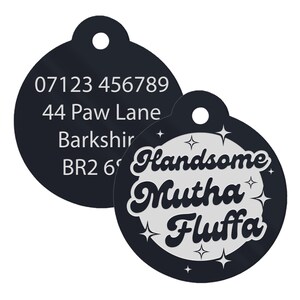 Op de afbeelding: Twee zwarte ronde huisdier-ID-tags. Een tag heeft een telefoonnummer, een adres en de tekst "Bark shire BR2 6". De andere tag heeft de tekst "Handsome Mutha Fluffa" in een zilveren, retro-lettertype met sterren rond de tekst.