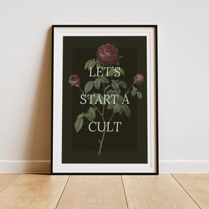 May include: A black and white framed print with a dark green background featuring a stylized illustration of a rose bush with the text "Let's start a cult" in white.
