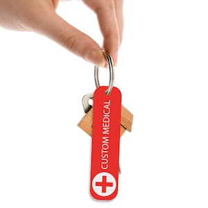May include: Red keychain with a white medical cross and the text "CUSTOM MEDICAL" on a white background.