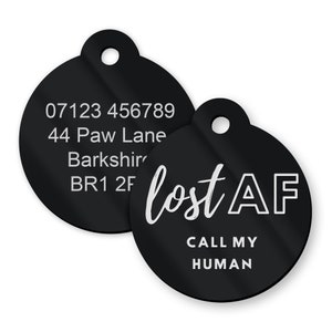 May include: Two black round pet ID tags with white text. The first tag has a phone number, address, and postcode. The second tag says "lost AF" and "CALL MY HUMAN".